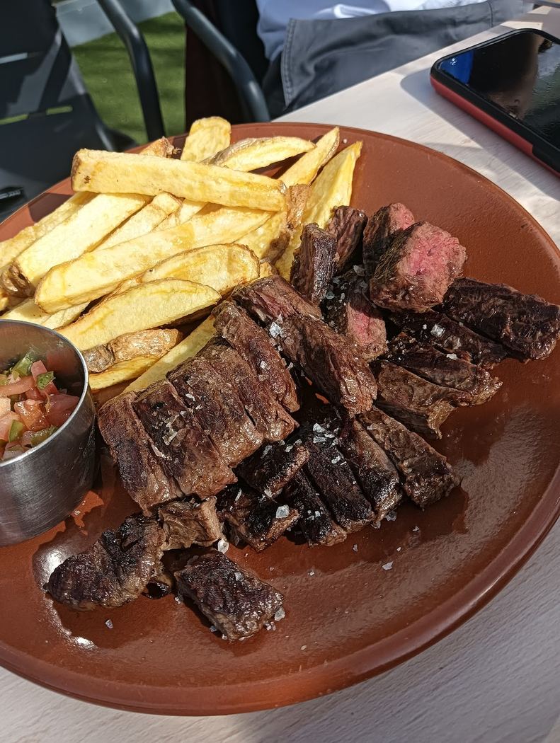 Entrecot a la plancha cortado en tacos, servido con patatas fritas y salsa criolla.
