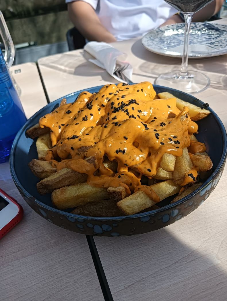 Patatas bravas con salsa especial de la casa y semillas de sésamo negro.
